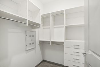 A walk in closet with white walls and white drawers and