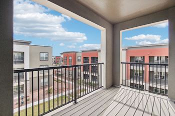 A balcony with a view of a yard and apartment buildings