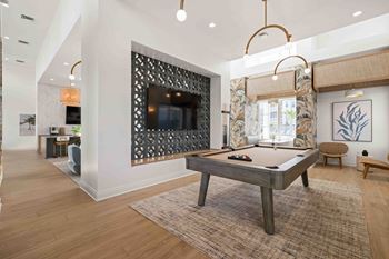 A pool table is in the middle of a room with a television and a chair