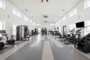 Vero Beach apartment for rent - A spacious gym with a variety of exercise equipment and a person working out at Verity Luxury Apartments, Florida
