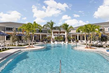 A large swimming pool in front of a building with palm trees