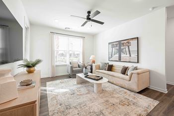 A living room with a beige couch, a rug, and a painting on the wall