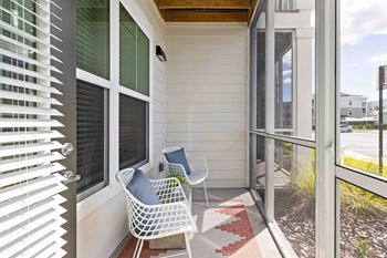 A white chair with a blue pillow is on a porch