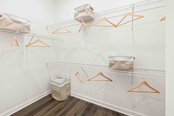 A white closet with orange hangers and a trash can