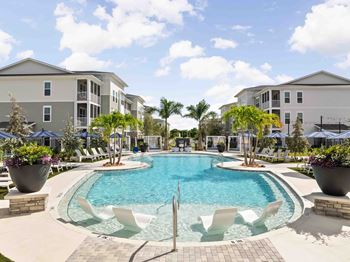 A swimming pool surrounded by white chairs and palm trees