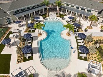 A large outdoor swimming pool surrounded by lounge chairs and umbrellas