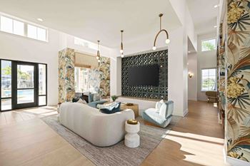A living room with a white couch and a black tv mounted on the wall