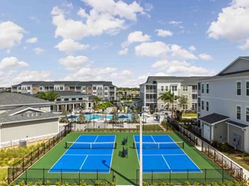 A tennis court is surrounded by a fence and apartment buildings