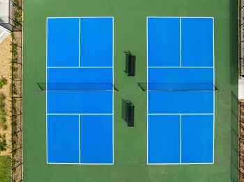 Two tennis courts with blue courts and black surroundings