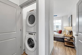 A front loading washer and dryer in a living room with a bedroom