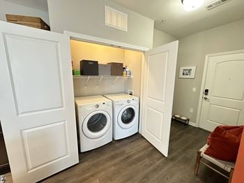 A laundry room with a washer and dryer and a shelf over the door
