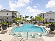 Vero Beach apartment for rent - A swimming pool surrounded by white chairs and potted plants at Verity Luxury Apartments, Vero Beach