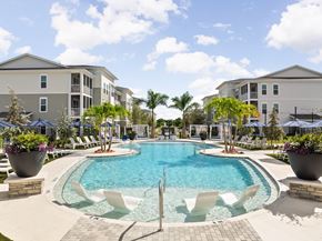Vero Beach apartment for rent - A swimming pool surrounded by white chairs and potted plants at Verity Luxury Apartments, Vero Beach