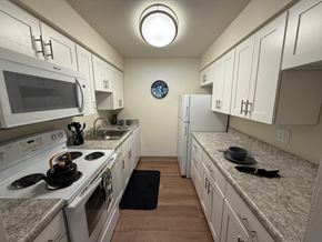 Monroeville apartment for rent - A kitchen with white cabinets and a round clock on the wall.
