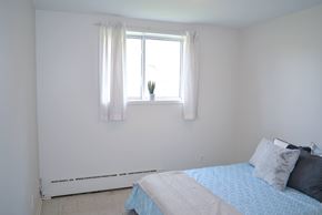 Winnipeg apartment for rent - Cozy bedroom with large window and white curtains offering natural light at 359 Edison Apartments.