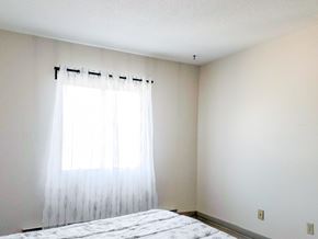 Winnipeg apartment for rent - A well-lit bedroom featuring a large window with sheer curtains at 1025 Munroe Apartments in Winnipeg.