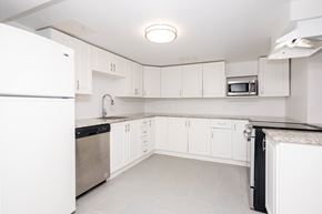 Winnipeg triplex for rent - A white kitchen with a refrigerator on the left and a microwave on the right.
