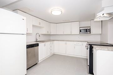 Winnipeg triplex for rent - A white kitchen with a refrigerator on the left and a microwave on the right.