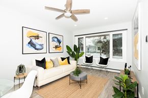 Winnipeg apartment for rent - A living room with a white couch, two chairs, a coffee table, and a ceiling fan.