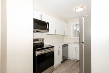 Winnipeg townhouse for rent - A kitchen with white cabinets and a black stove top oven.