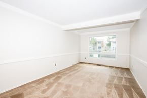 Winnipeg apartment for rent - A room with a carpeted floor and a window showing a view of buildings outside.