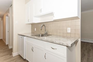 Winnipeg apartment for rent - A kitchen with white cabinets and a marble countertop.