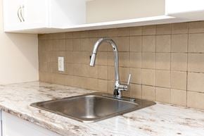 Winnipeg apartment for rent - A kitchen sink with a chrome faucet on a marble countertop.