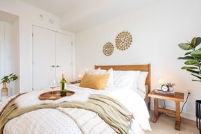 Winnipeg apartment for rent - A cozy bedroom with a large bed and a tray with a bottle and glasses on it.