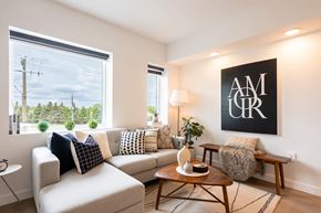 Winnipeg apartment for rent - A living room with a couch, a table, and a large window with a view of trees and power lines.