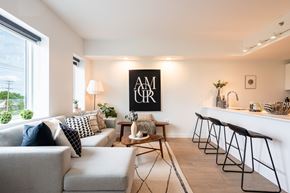 Winnipeg apartment for rent - A modern living room with a grey sofa, a coffee table, and a bar area with stools.