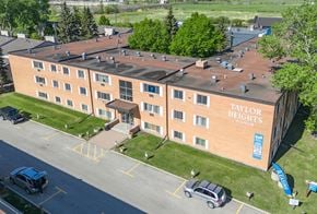 Winnipeg apartment for rent - A Taylor Heights Manor building with a parking lot in front.