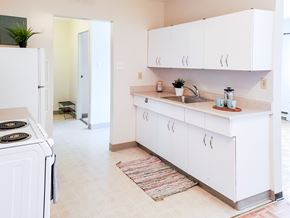 Winnipeg apartment for rent - A bright and spacious kitchen with white cabinets, a stainless steel sink, and ample storage at 1025 Munroe pet-friendly apartments in Winnipeg.