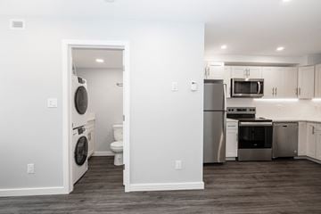 Winnipeg apartment for rent - a white kitchen with a washer and dryer and a stainless steel refrigerator