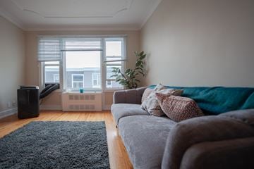 Winnipeg apartment for rent - A living room with a grey couch and a black speaker.