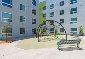 San Ysidro apartment for rent - A playground with a swing set and two benches in front of a building.