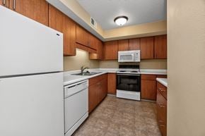 West Des Moines apartment for rent - A kitchen with a white refrigerator, brown cabinets, and a white stove top oven.