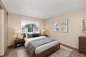 West Des Moines apartment for rent - A bedroom with a large bed, two lamps, and a painting on the wall.