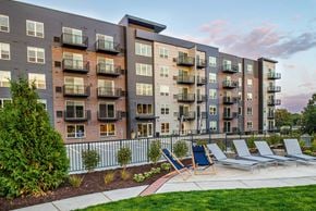 Minnetonka apartment for rent - Exterior view of a modern six-story apartment complex featuring a harmonious blend of brick and metal siding. The architectural design showcases a contemporary aesthetic with clean lines and a mix of materials.