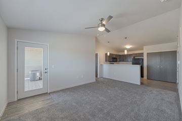 Sioux Falls apartment for rent - A spacious living room with a grey carpet and a ceiling fan.