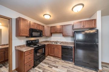 Sioux Falls townhouse for rent - a kitchen with black appliances and wooden cabinets