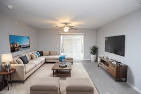 Sioux Falls apartment for rent - A living room with a large couch, a coffee table, and a flat-screen TV mounted on the wall.