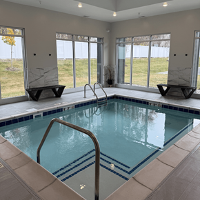 Sioux Falls apartment for rent - A large indoor swimming pool with a glass wall and a metal ladder.