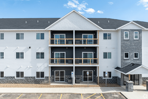 Sioux Falls apartment for rent - A white building with a black roof and a parking lot in front.