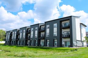 Sioux Falls apartment for rent - A modern apartment building with balconies and a grassy area in front.