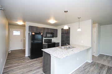 Sioux Falls apartment for rent - A kitchen with a black refrigerator and a sink.