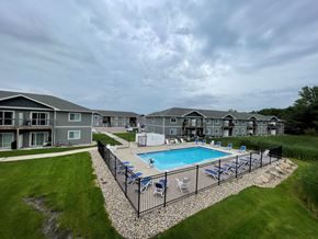 Sioux Falls apartment for rent - A swimming pool surrounded by a black fence and lounge chairs.