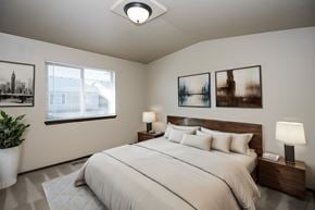 Sioux Falls townhouse for rent - A bedroom with a large bed, two lamps, and three pictures on the wall.