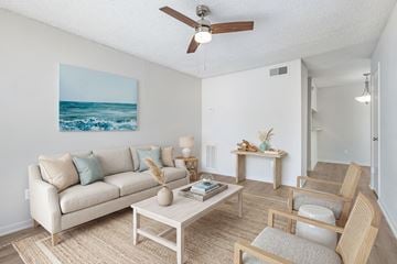 Houston apartment for rent - A living room with a beige couch, a coffee table, and a painting of a beach scene on the wall.