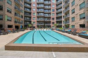 Houston apartment for rent - A large swimming pool in front of a multi-story apartment building.