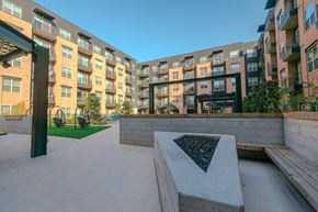 Dallas apartment for rent - A modern courtyard with a bench and a table surrounded by buildings.